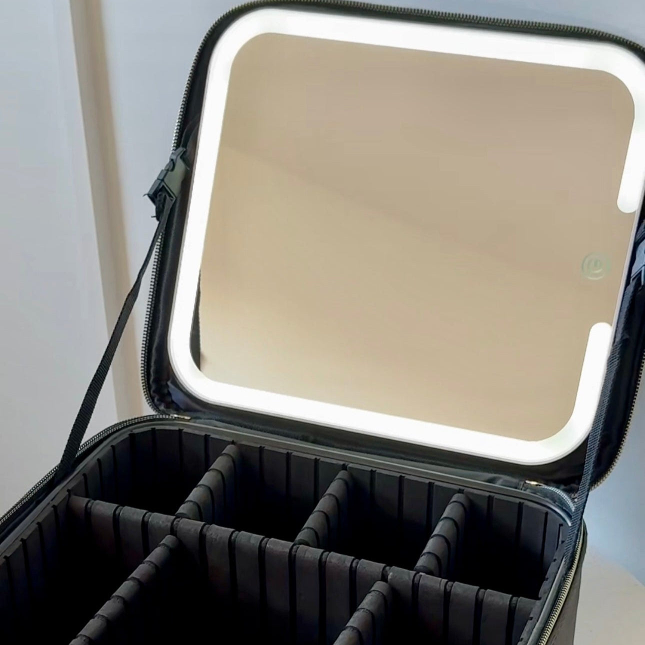 Black makeup case with mirror on a white surface